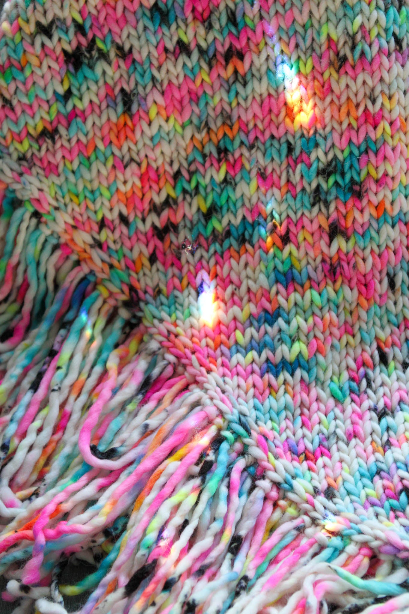 Close-up of Garden Graffiti shawl, hand-dyed stitches and soft fringe in neon 
colorway.