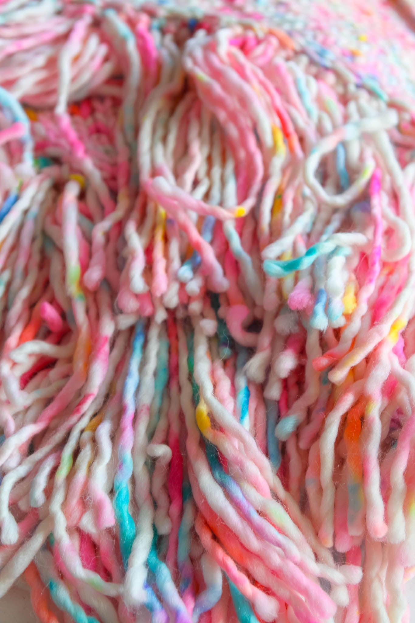 Close-up of colorful yarn with pink, blue, and multicolor strands. fringe designed for balance and drape