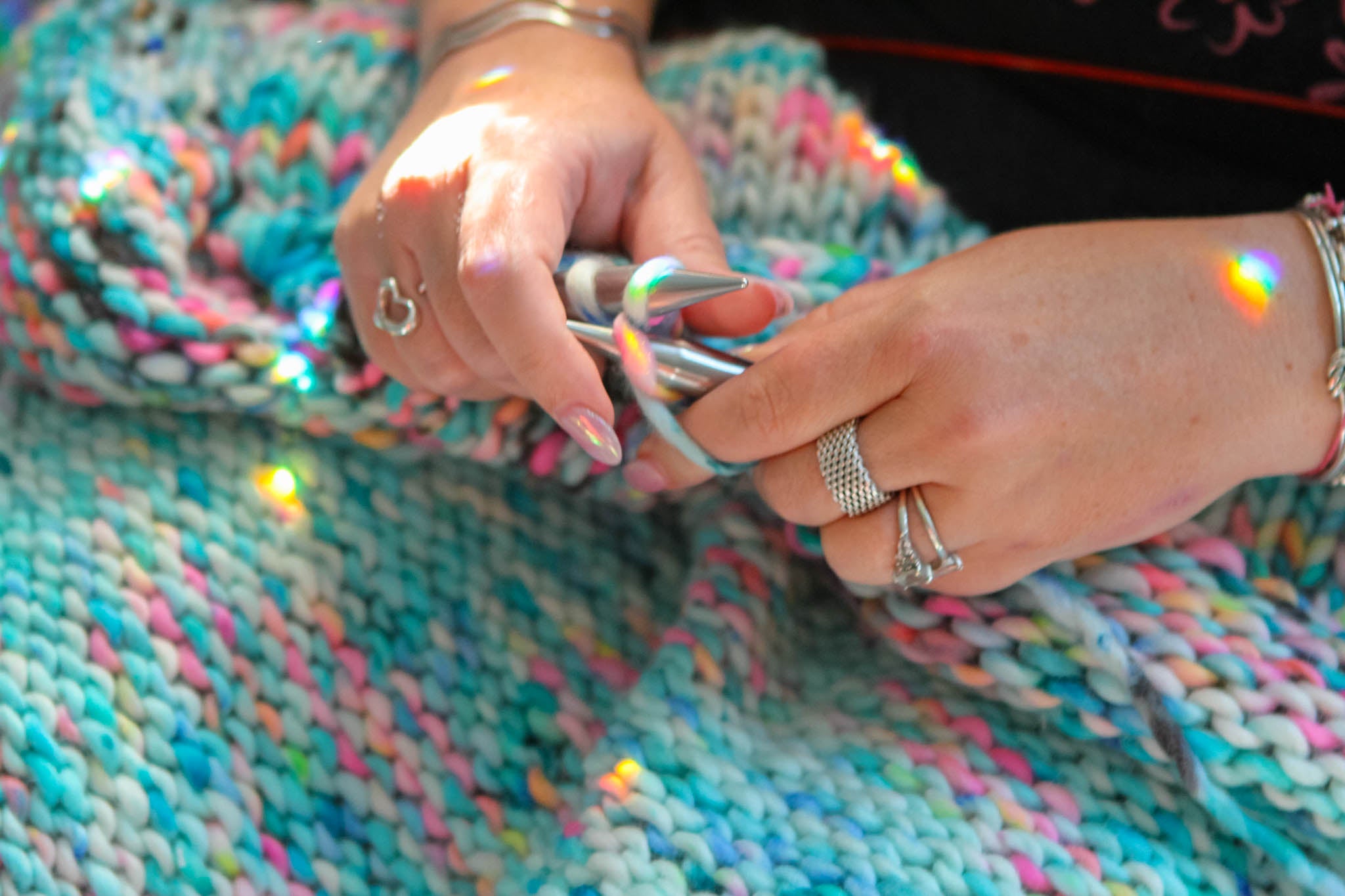 Close-up of hands knitting with colorful yarn and knitting needles. slow fashion, hand knit, couture craftsmanship, limited edition