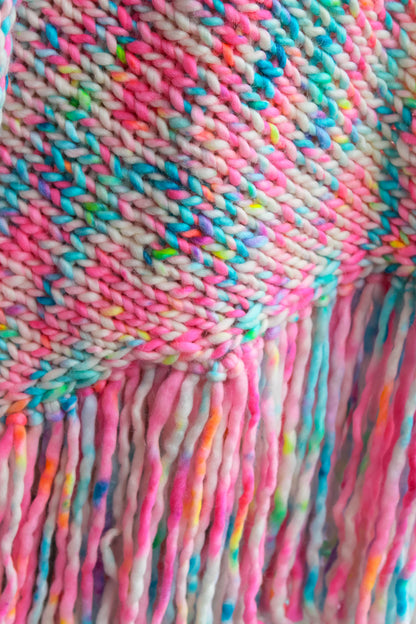 Close-up of a colorful knitted fabric with fringes. hand knit, inspired by wildflower, art fashion, limited edition shawl