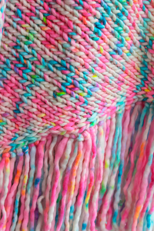 Close-up of a colorful knitted fabric with fringes. hand knit, inspired by wildflower, art fashion, limited edition shawl