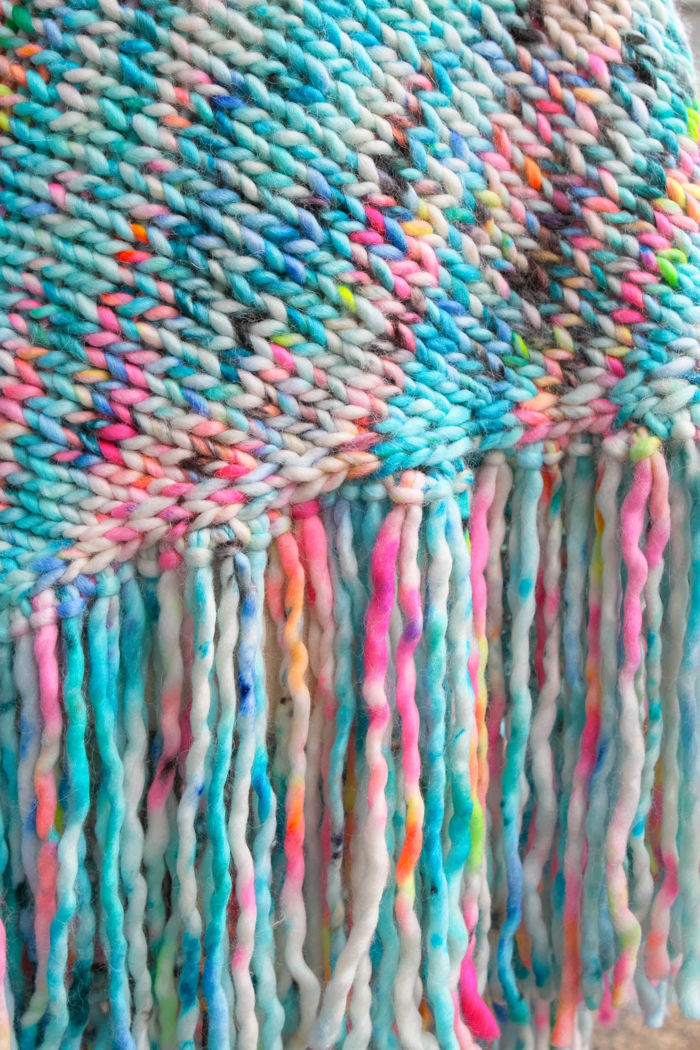 Close-up of a colorful woven fabric with fringes. neon reef, ocean inspired, hand dyed, luxury wrap