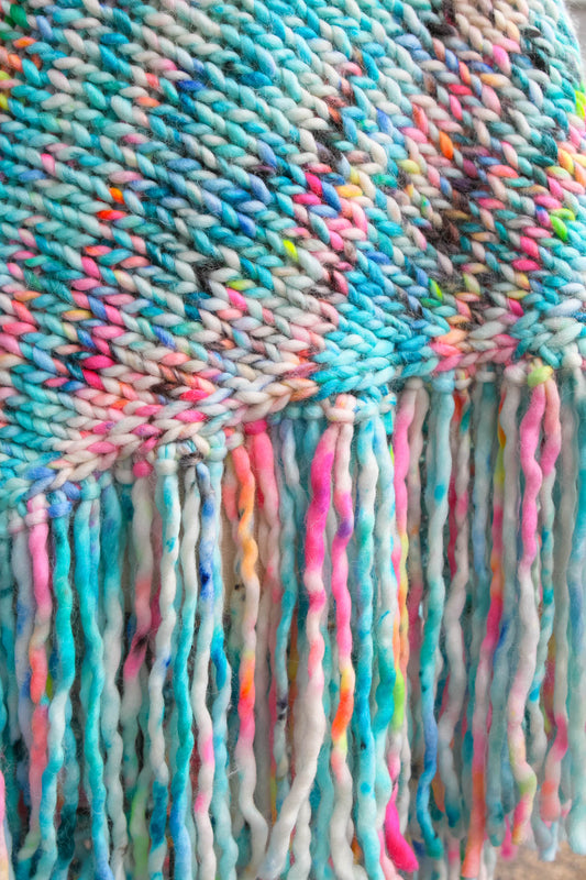 Close-up of a colorful woven fabric with fringes. neon reef, ocean inspired, hand dyed, luxury wrap