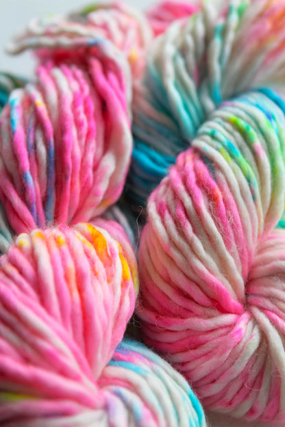 Close-up of colorful yarn skeins with pink, blue, and multicolor patterns.