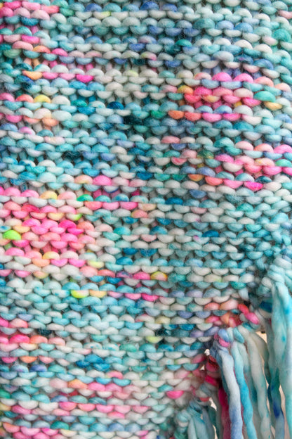 Macro shot of Neon Reef knit pattern — bold turquoise and coral stitches in luxury yarn